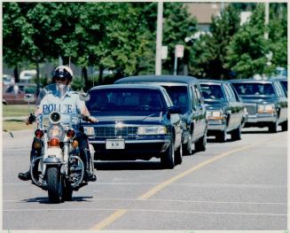Weeping mourners: Escorted by a policeman, the funeral procession bearing the Grade 6 student's coffin leaves a Brampton church