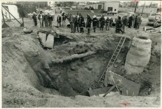 Gas crater: Firemen, police and workmen check hole 15 feet deep by 20 feet across created by escaping gas from a ruptured main today