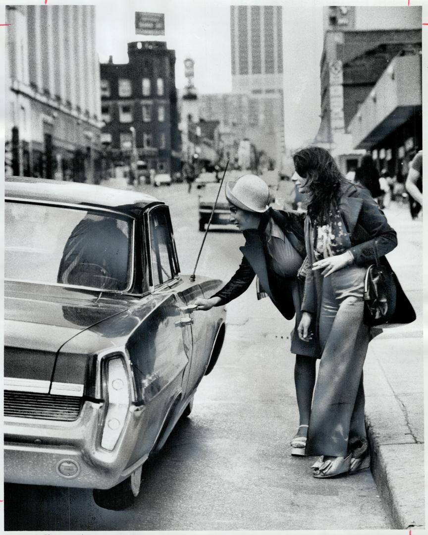 Hitchhiking is under attack. Hitchhiking home, Marsha Caravan, 20, opens a car door as she and her sister Maria, 19, get a ride on Yonge St. Metro Pol(...)