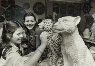 Nancy Spratt, 17, watches as Carol Roach, 10, paints a plaster cheetah