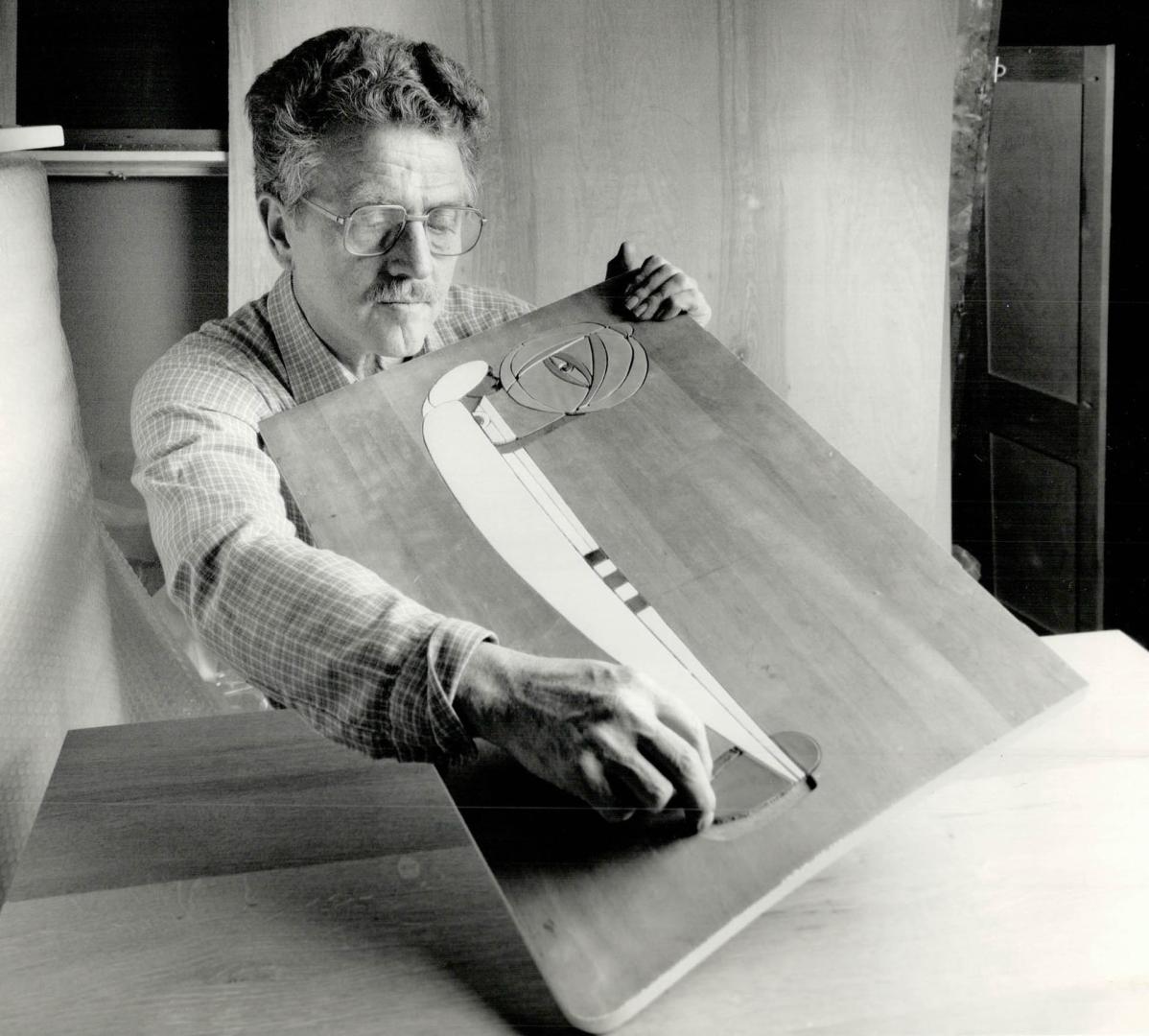 Decorative inlay: Above, Toronto woodworker and craftsman Walter Putzer checks colored glass inlay on inside of door for a cabinet