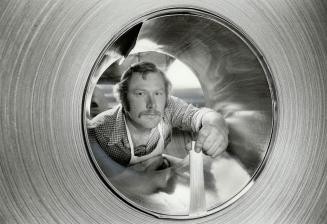 Looking ahead Employee Lionel Mokry peers through rolled coil of aluminum, which will be converted into toothpaste tubes and the like, at Algoods, Alc(...)