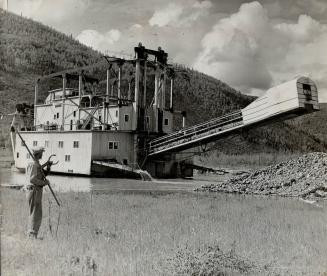 The oldest dredge in the Yukon is seen in action handling gravel on one of the creeks