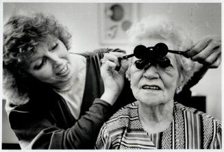 New outlook: CNIB vision rehabilitation nurse Elaine Taylor adjusts a pair of special binoculars designed to enhance 83-year-old Janet Morgan's sight