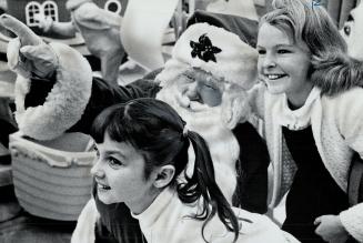 Santa shows Beverley Clark, Faye Marks features of his colorful parade, Twenty floats, clowns