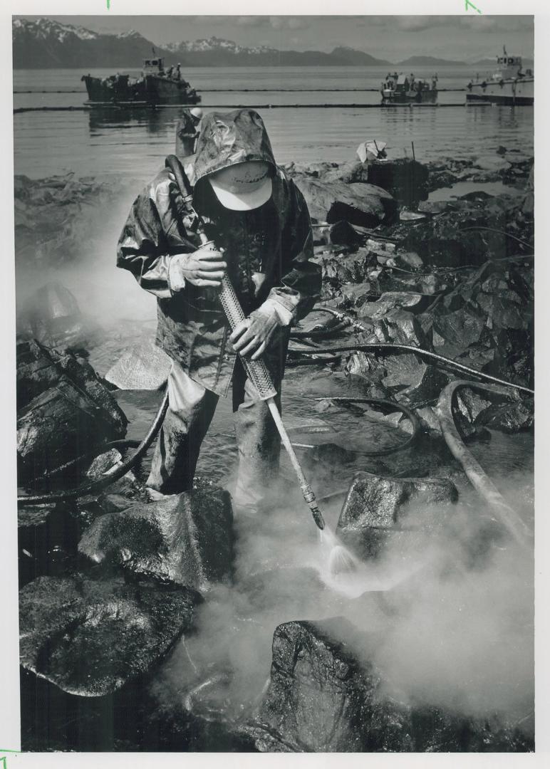 Using a jet of hot water, a worker tries to scrub crude oil from the rocky shore of Green island, 112 kilometres (70 miles) southeast of Valdez, Alask(...)