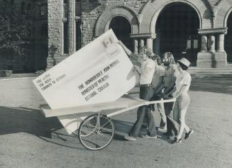Students begin long march with giant brief, Trundling a handcart, four students left the Legislature today bound for Ottawa with a giant envelope cont(...)