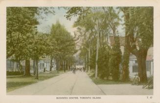 Picture of tree lined main street with shops on either side and people walking on street in the ...