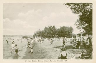 People, mostly children, playing in the water and sand, some swimming, on a sandy beach.