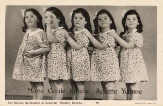 Black and white photograph of five identical little girls in matching floral dresses.