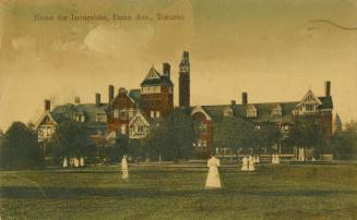 Colorized photograph of a large multi-winged hospital building with people dressed in white out…