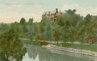 Colorized photograph of a large hospital complex taken from below in a valley with a river. 