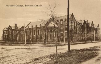 Sepia toned picture of a four story school building with a house behind it.
