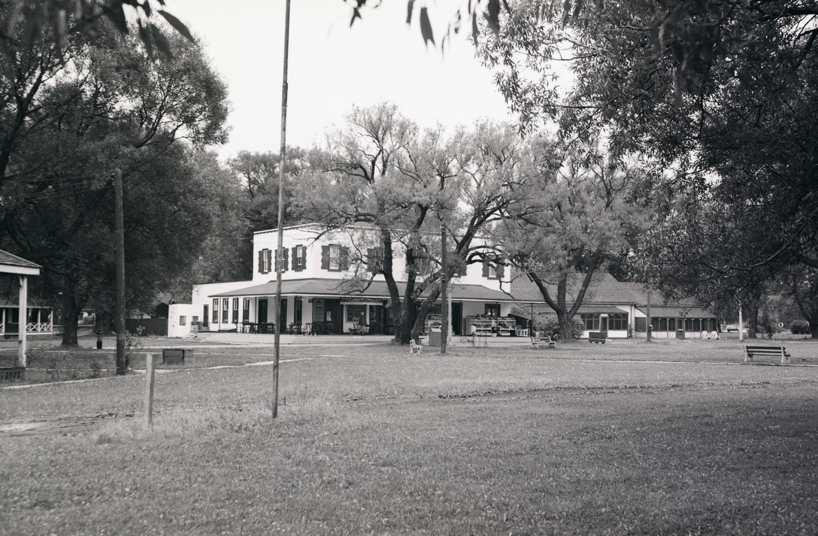 A mid-range distance photo of the Ward's Island hotel, a large two-storey structure with a wrap ...