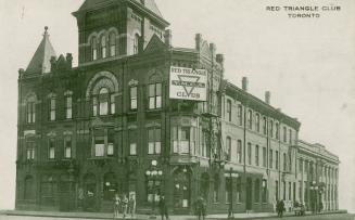 Black and white photograph of the corner of a three story, brick building with a central tower.