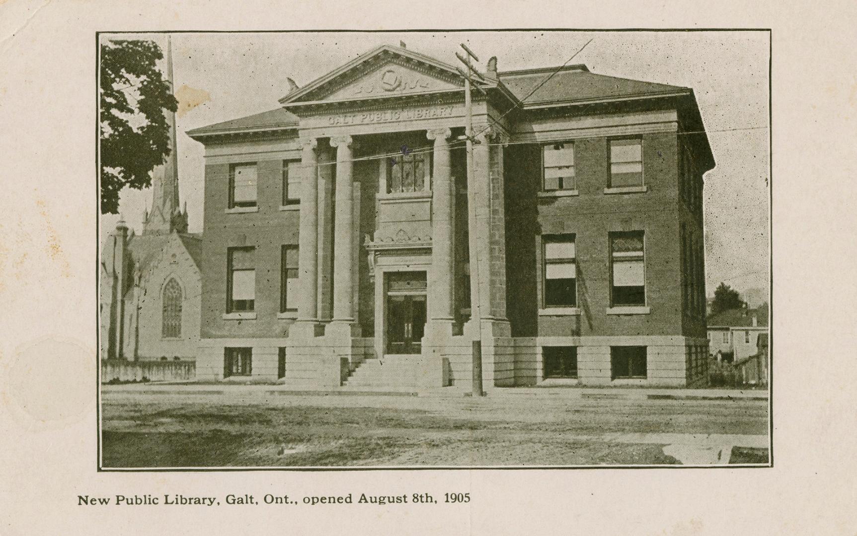 Picture of two story library with large front pillars and church building with spire to the lef ...