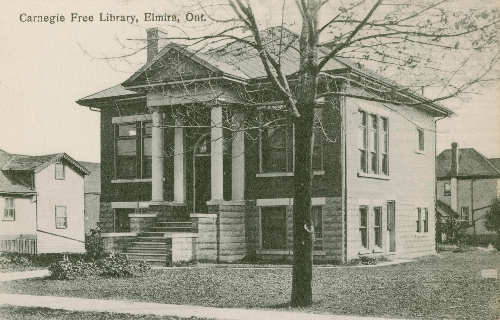 Picture of public library building with four pillars at front door and large tree on lawn and a ...