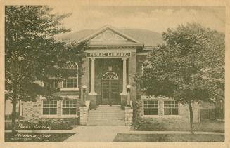 Picture of two storey library building with pillars at front and trees on front lawn.