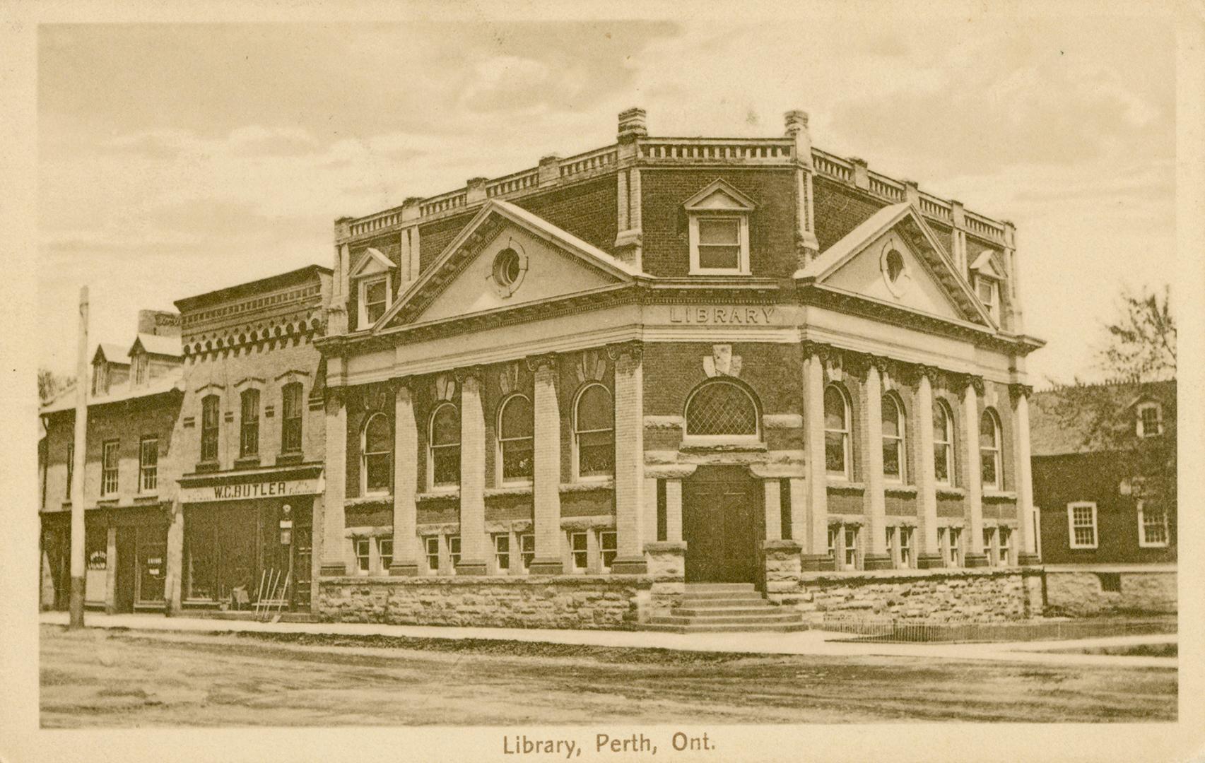 Picture of street with three storey library on the corner and stores to the left and building t ...