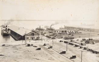 A photograph of a harbour and port area, with several ferries either docked or approaching the  ...
