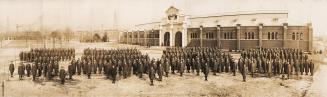 A photograph of a military regiment standing in front of a large building with a sign over the  ...