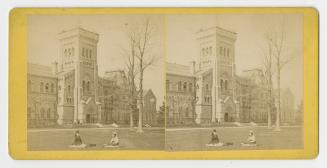 Pictures show two women sitting on the lawn in front of a huge collegiate-gothic building.