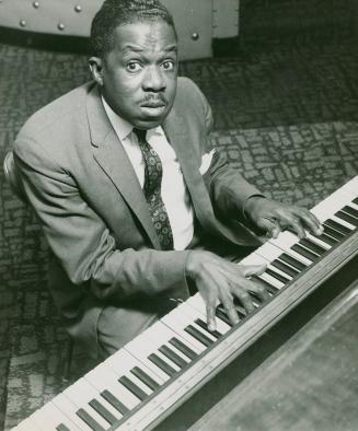 Cy McLean plays the piano while looking into the camera