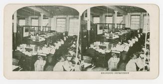 Two photographs of the interior of a room where several people are working at desks, with card  ...