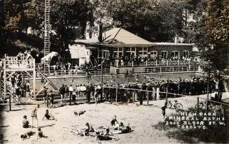 Black and white photograph of a large crowd of people surrounding a public swimming pool.