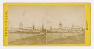 Pictures show a long low-rise public building with three towers beside a body of water.