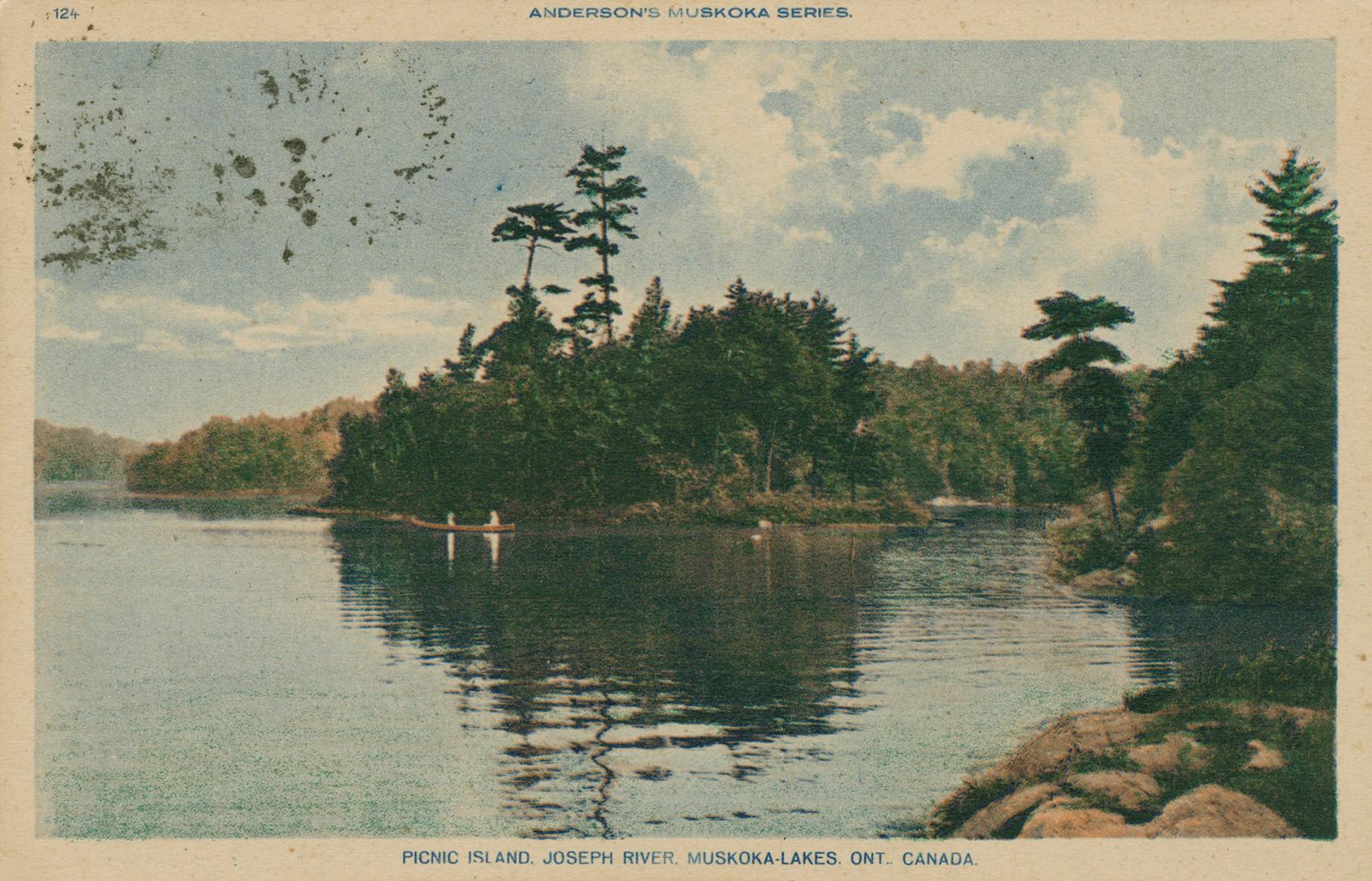People canoeing near the wooded shoreline of a lake.