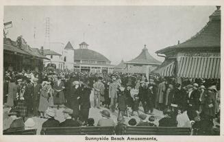 Picture of crowds walking around buildings at an amusement park. 