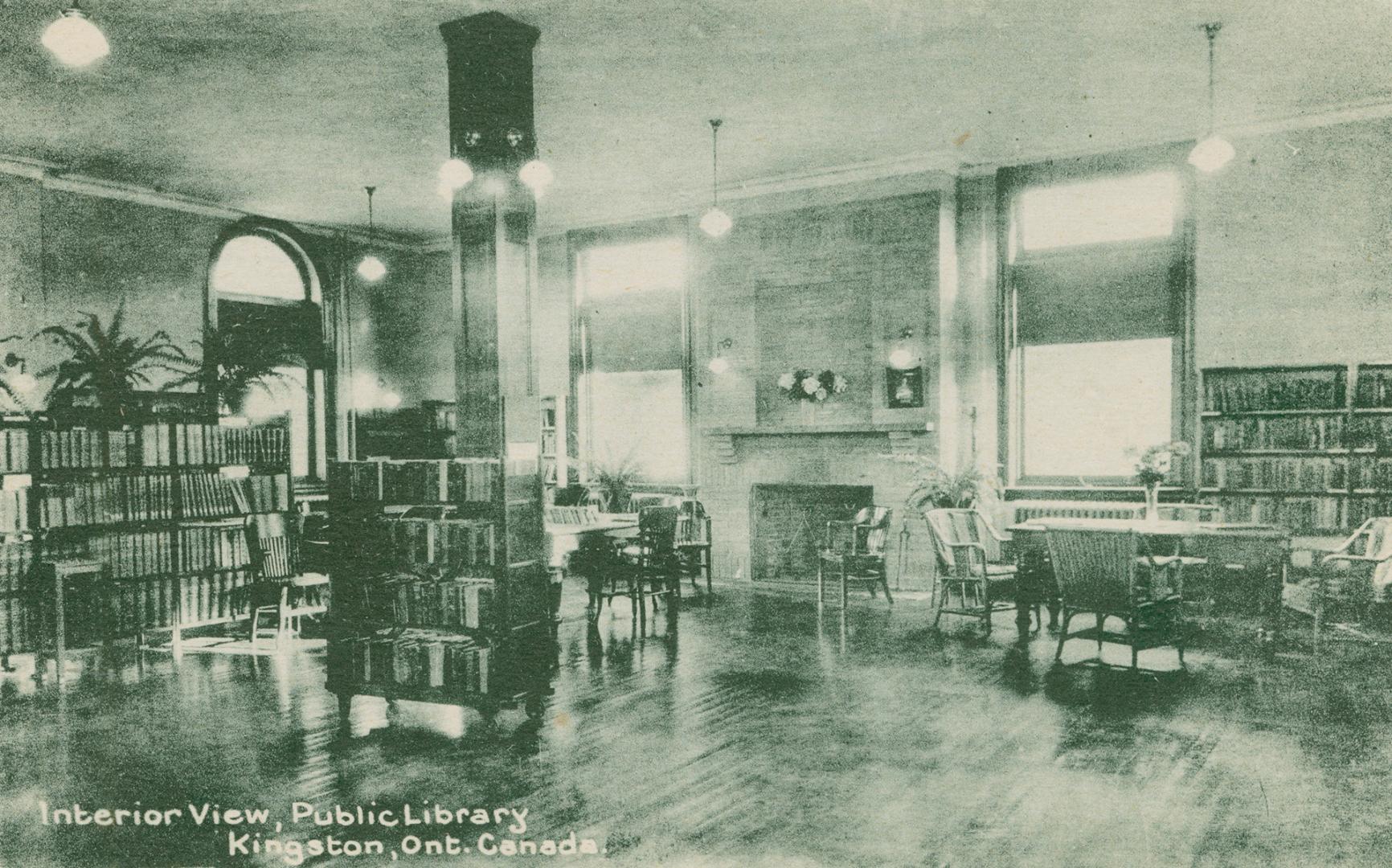 Picture of room in a library with tables, books and fireplace. 