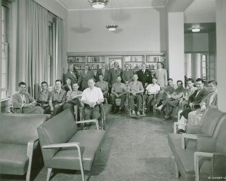 A group of men sit and stand in rows. 