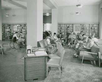 Men sit reading in a library. 