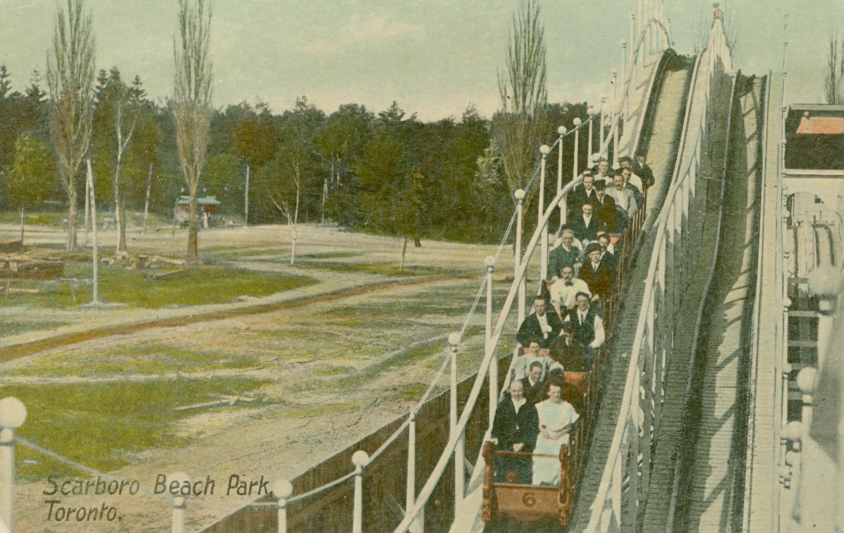 People riding a roller coaster in a park setting.