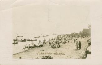 Picture of people on a beach with many boats in the water. 