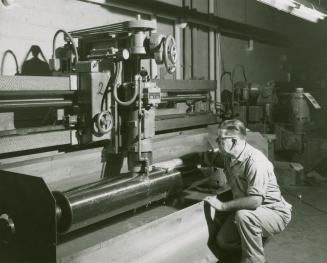 A photograph of a man with one hand on a rotary press during the process of printing Simpsons-S ...