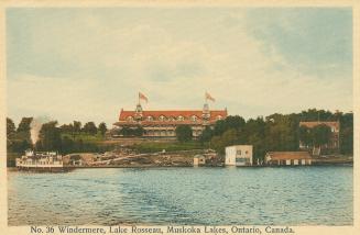 A steamer on a lake in front of a very large hotel.