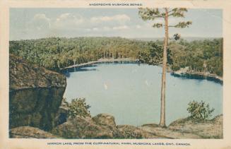Birds-eye view of sail boats on a lake in a remote setting.