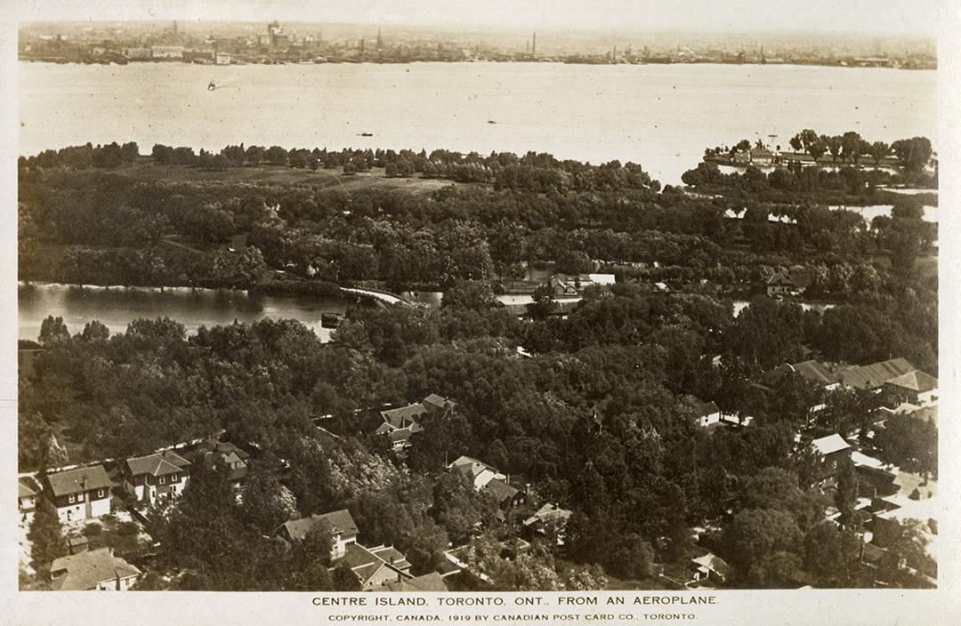 Aerial shot of houses on land beside a lake. B & W.
