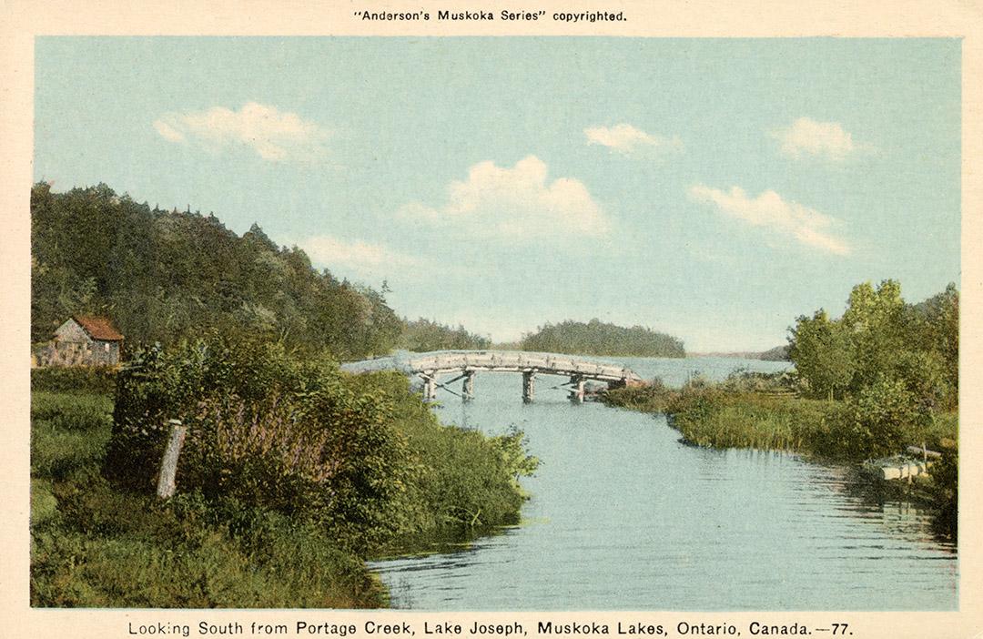 A wooden bridge spanning a narrow stream of water running into a lake.