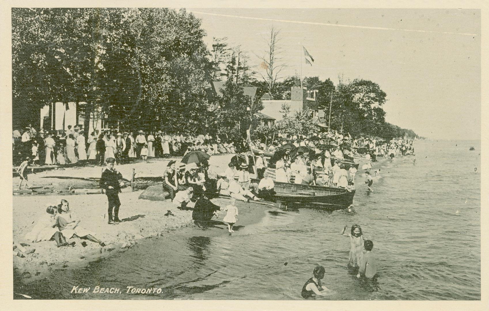 Black and white picture of a crowded beach beside a body of water.