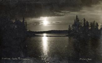 Black and white photograph of sunrise over a lake in the wilderness.
