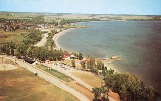 Color photograph of a road and a beach beside a lake.