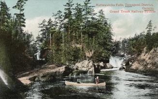 Colorized photograph of two men paddling a canoe in a lake in the wilderness. 