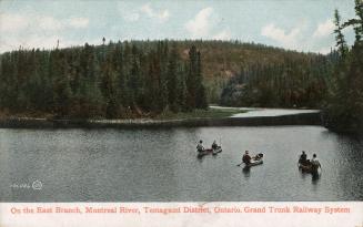 Colorized photograph of five men in three canoes on a lake in the wilderness. 