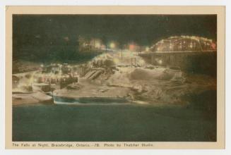 Colorized photograph of lights on a bridge over a waterfall; taken at night. 