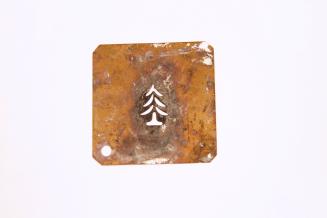 A small brass square with the image of a pine tree cut out in it.