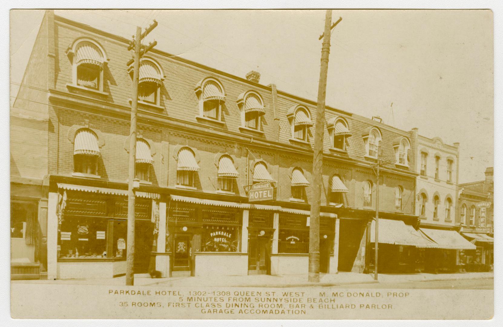 Black and white picture of a three story hotel building with shops on the ground floor.